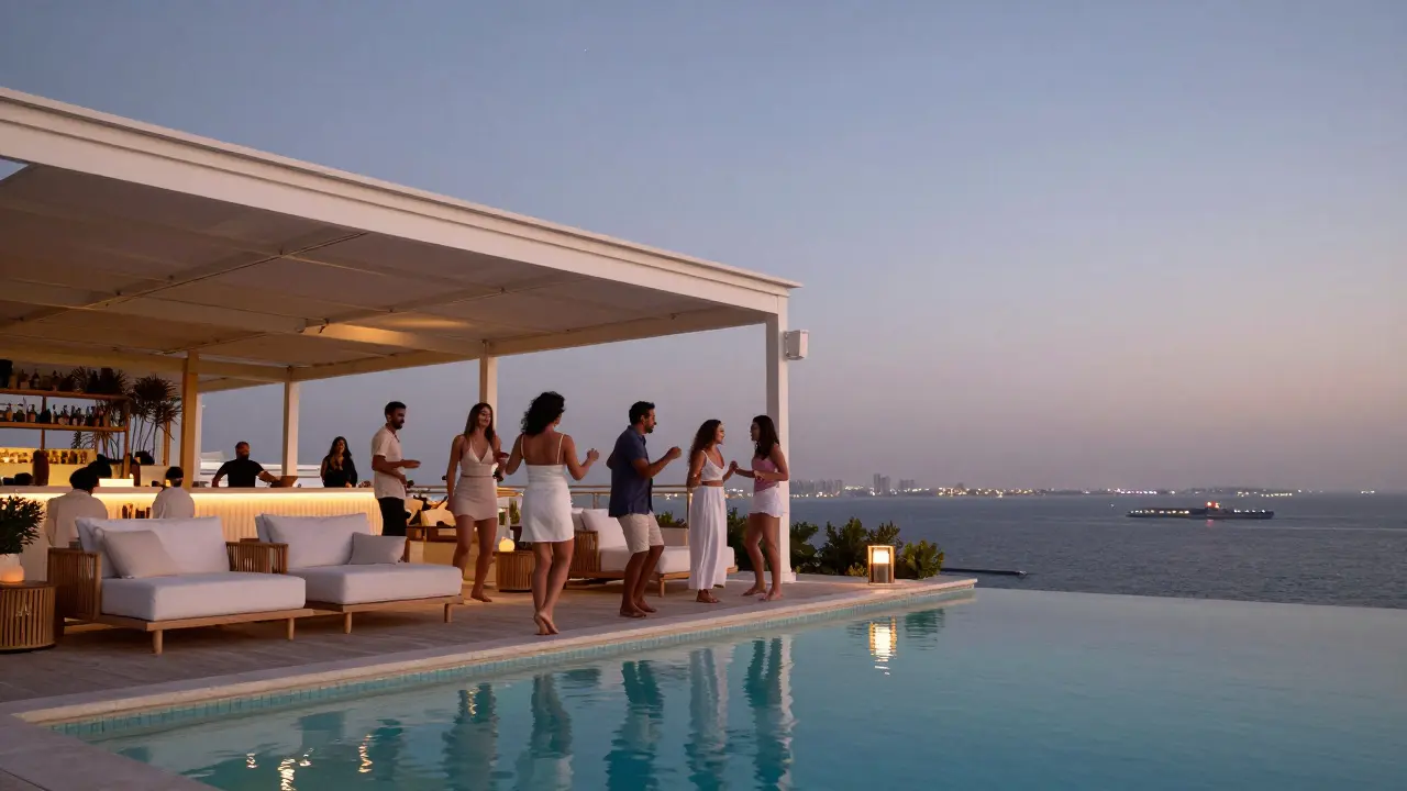 Guests dancing barefoot on a rooftop terrace overlooking the Persian Gulf at twilight, soft lights reflecting on water.